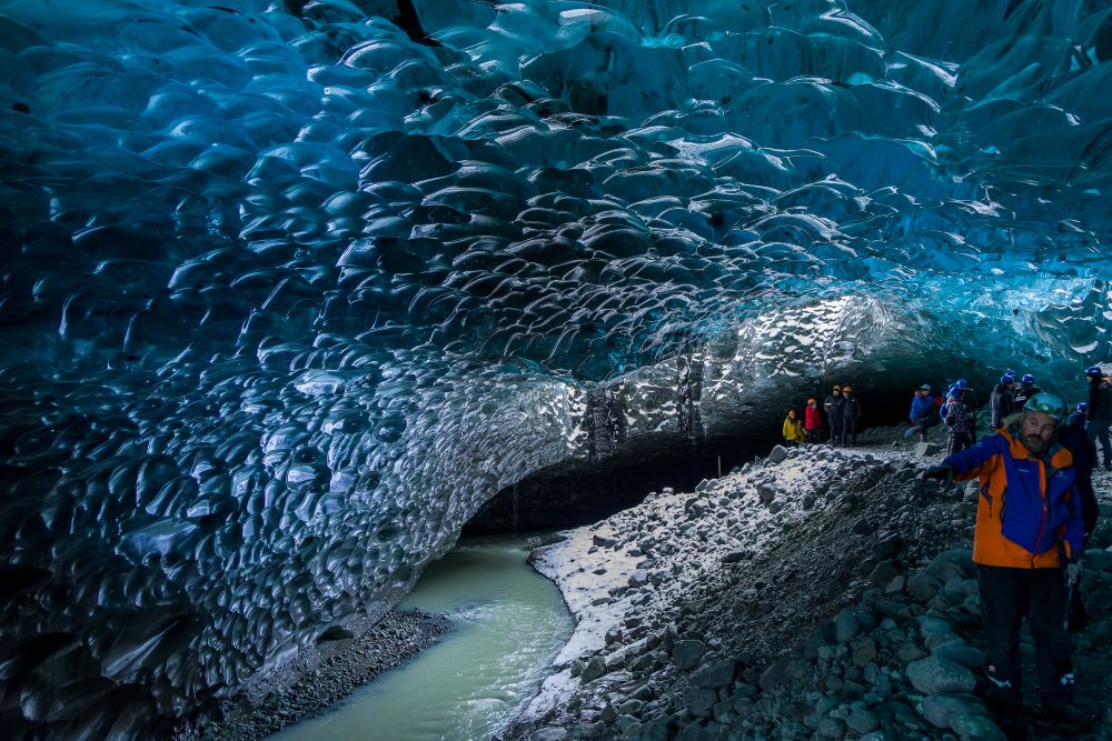 Menschen bestaunen das blau schimmernde Eis in einer Gletscherhöhle in Island