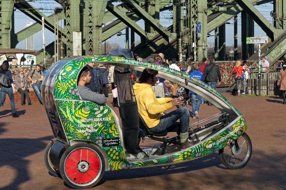Rikschafahrer mit 2 Gästen an der Hohenzollernbrücke in Köln