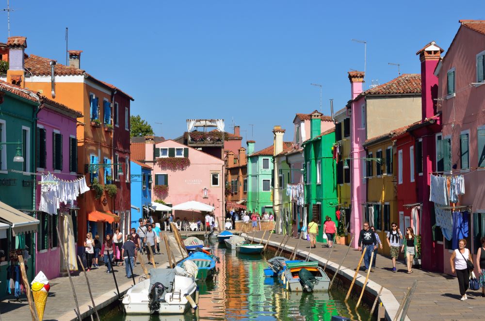 Touristen spazieren entlang der bunten Häuser von Burano